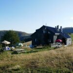 Espace extérieur aménagé du refuge de montagne, sur le plateau des Vosges, face à un vaste panorama de forêts et de crêtes.