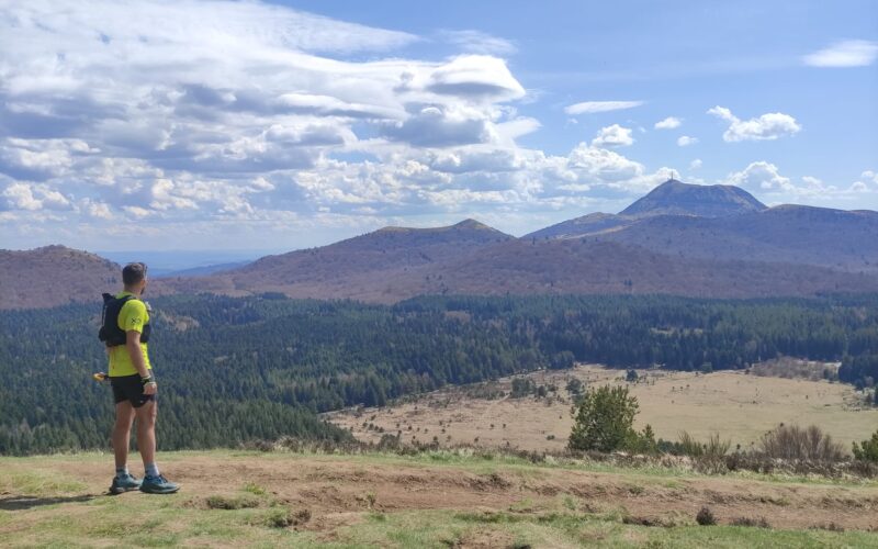 Participant courant sur un sentier de trail dans les Volcans d'Auvergne.